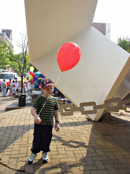 A child stands in front of the Metamorphosis sculpture on Houdini Plaza during a quiet moment at Houdini Days.