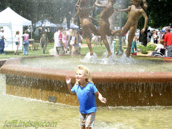 A girl frolicks in the famous water fountain in City Park during the Art in the Park festival.