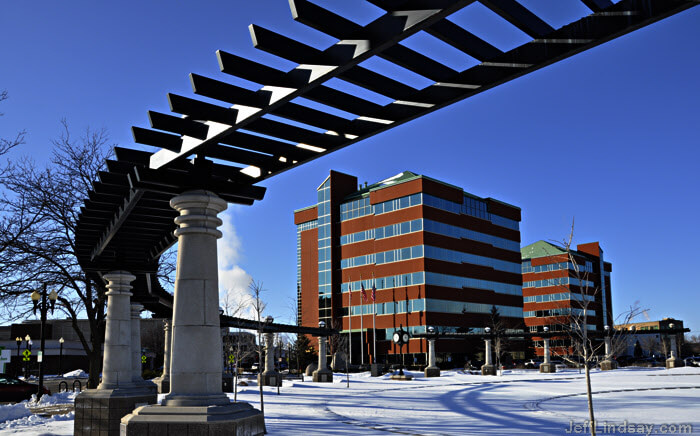 Downtown Neenah, showing one of the Neenah Center buildings and a portion of a park near the water, on the north side of Wisconsin Avenue.