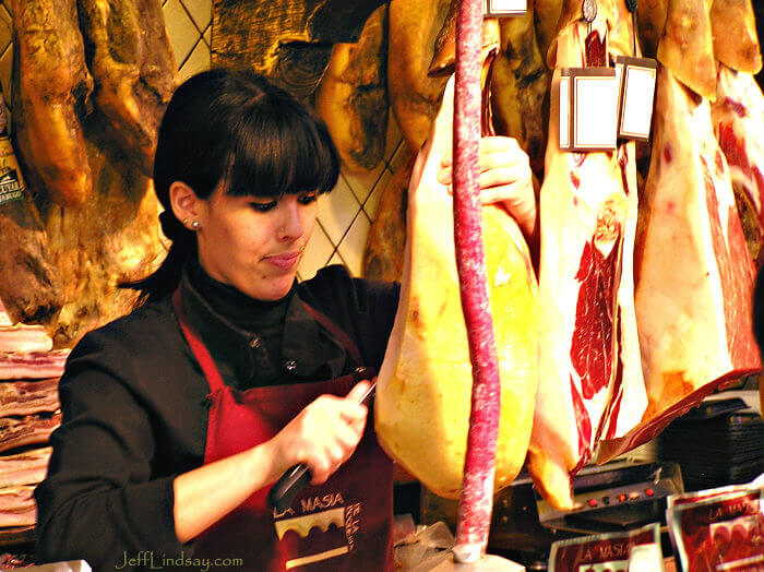Woman preparing meat at a meat shop in Barcelona's central market, March 2009.