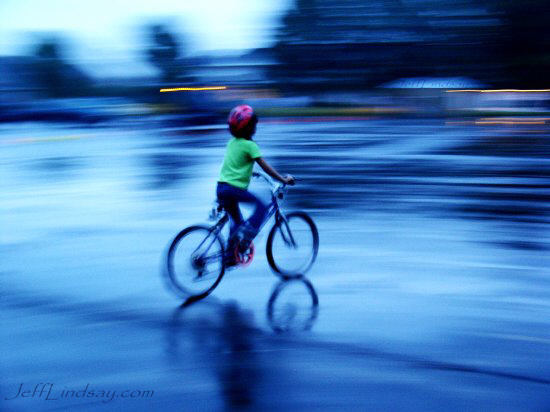 Girl on a bike in the rain, evening, Aug. 2004.