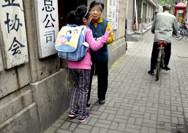 A grandmother sends her granddaughter off to school in downtown Shanghai.