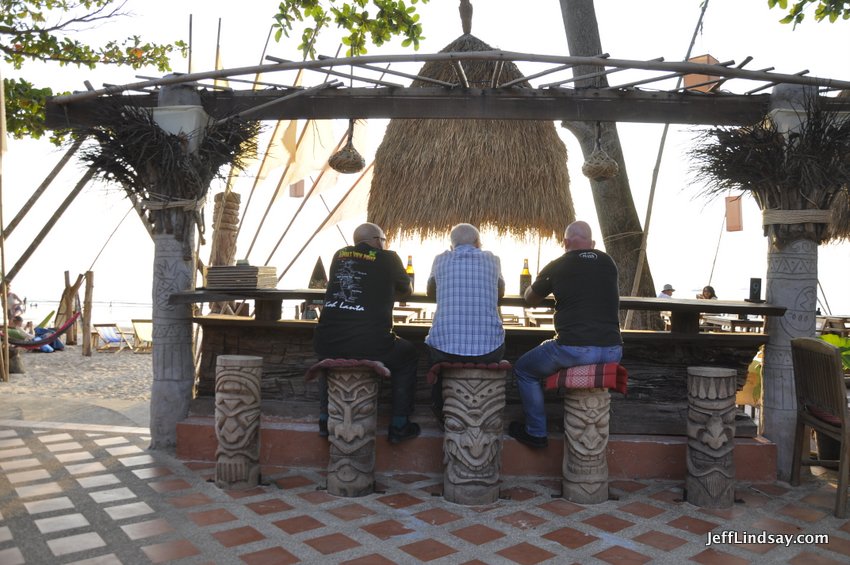 Three friends enjoying conversation and drinks on the beach, west side of Lanta Island, Thailand. Jan. 2017.