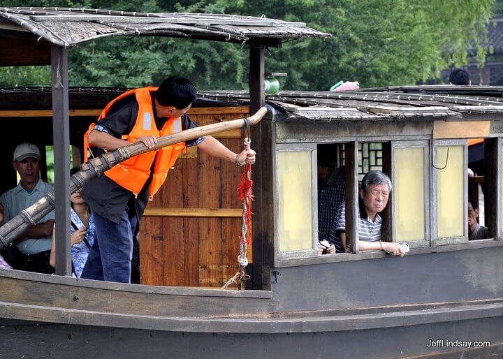 A boat at Wuzhen, China, with a happy tourist.