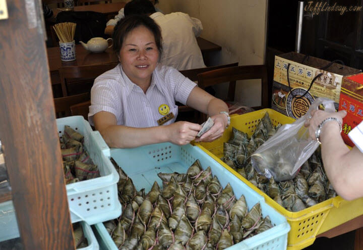 Woman selling zhongzi, triangular packs of rice and other ingredients wrapped in banana leaves and steamed. Inexpensive and delicious.