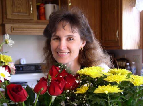 Kendra in front of some flowers in the kitchen.