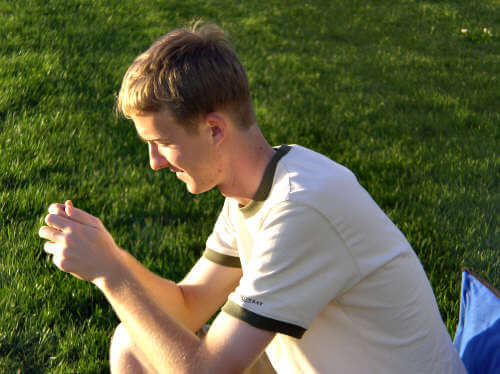 Stephen prepares to make a loud and often annoying whistling sound using a blade of grass during a soccer game, July 2004.