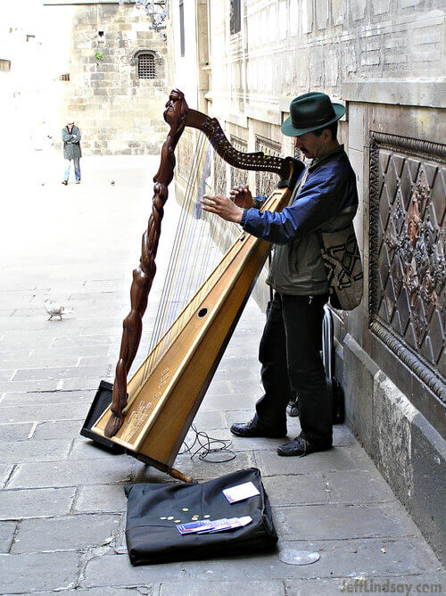Street musician playing a harp in the old city of Barcelona, Spain. March 2008.