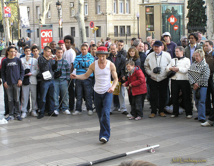 A street performer from Australia preparing to do stunts on a pole before a crowd on La Rambla in Barcelona.