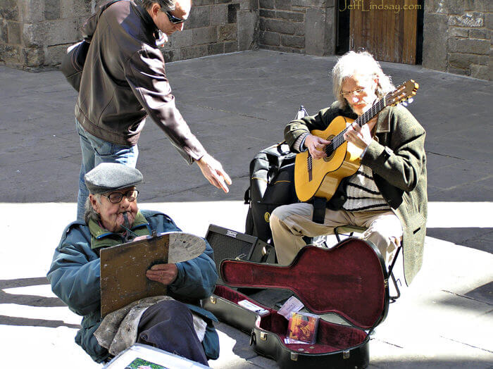 Two artists on a square in the Old City of Barcelona - guitar player and painter.