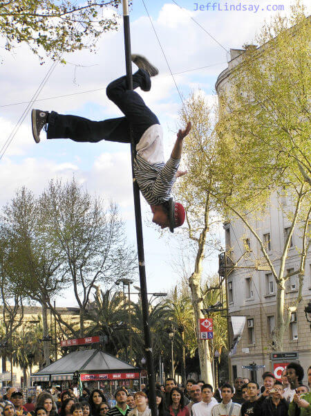 The street performer in action. The pole is held by four cables with volunteers on each end.