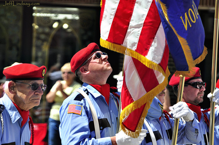 Veterans carrying and looking up to the flag.